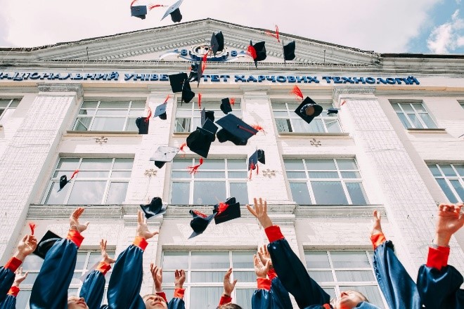 Image of graduating students throw their caps in the air.